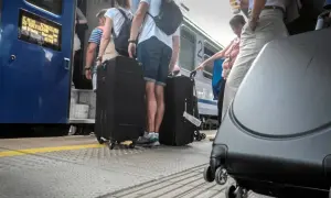 Ludzie z dużymi walizkami na peronie PKP, wsiadający do pociągu.