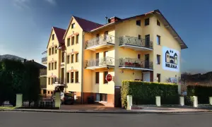 Żółty budynek hotelu Milena w Milówce z balkonami i logo hotelu.