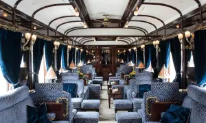 Luksusowe wnętrze wagonu kolejowego, gdzie pociągiem z Warszawy można poczuć się jak król. Błękitne fotele i aksamitne zasłony tworzą atmosferę elegancji.