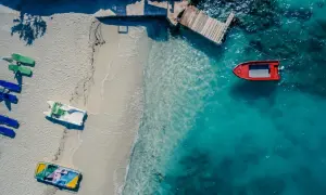 Widok z lotu ptaka na plażę z łodziami i turkusową wodą. Golem Albania atrakcje to idealne miejsce na wakacje.
