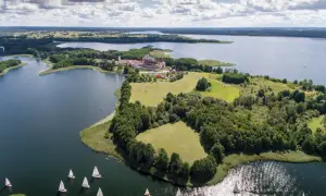 Żaglówki na jeziorze koło pałacu w Krainie Wielkich Jezior Mazurskich. Nietypowe atrakcje Podlasia to także piękne krajobrazy i sporty wodne.