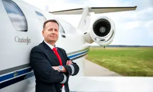 Pilot w mundurze z odznaką na rękawie opiera się o CitationJet. Marzysz, jak zostać pilotem?