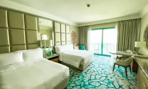 Pokój hotelowy z dwoma łóżkami, widokiem na balkon i ocean. Zastanawiasz się, ile kosztuje doba w hotelu?