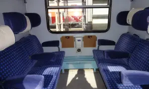 Wnętrze wagonu Intercity z niebieskimi siedzeniami. Czekam, aż zwolnią się miejsca dla niepełnosprawnych.