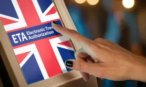 Dłoń dotyka ekranu z flagą Wielkiej Brytanii, gdzie widnieje napis "ETA Electronic Travel Authorization". To formularz na wjazd do Anglii.