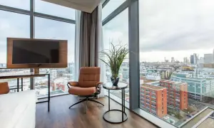 Wygodny fotel i telewizor w pokoju hotelowym z widokiem na panoramę Frankfurtu. Frankfurt Radisson Blu oferuje wspaniałe widoki.