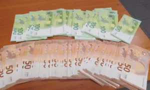 Stosy banknotów 100 i 50 euro na drewnianym stole. Taki widok może towarzyszyć przewozowi gotówki w strefie Schengen.