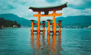 Pomarańczowa brama torii w wodzie, idealne miejsce na Japonia wycieczka. W tle góry i miasto.