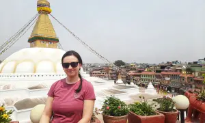 Kobieta w okularach przeciwsłonecznych pozuje na tle stupy Bodnath w Nepalu. Marzenie o lotach do Nepalu spełnione!
