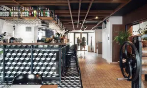 Nowoczesny bar w hotelu Almond. Geometryczne wzory na ladzie i podłodze, drewniany sufit, butelki alkoholi na półkach.