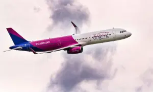 Samolot Wizz Air z charakterystycznym różowym pasem wznosi się na tle chmur. Wizz flex to jego motto!