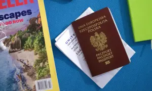 Polski paszport i bilet lotniczy na podróż do Kanady. Obok magazyn podróżniczy i zielony notatnik.