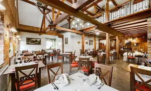 Przytulna restauracja w hotelu Młyn Elbląg. Drewniane belki, ceglane ściany i eleganckie stoły tworzą niepowtarzalny klimat.