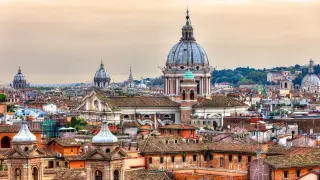 Rzym w listopadzie, z kopułami kościołów i budynków na tle zachmurzonego nieba.