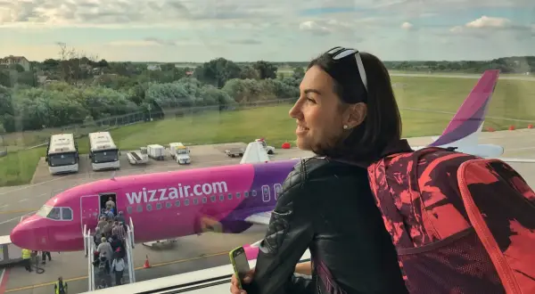 Kobieta z plecakiem patrzy na samolot Wizzair. Chcesz wiedzieć, jak zadzwonić do Wizzair za darmo? Sprawdź na stronie przewoźnika.
