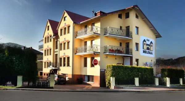 Żółty budynek hotelu Milena w Milówce z balkonami i logo hotelu.
