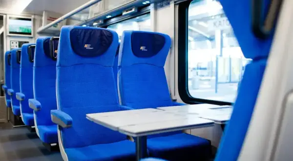 Wygodne siedzenia w pociągu PKP Intercity, gotowe na podróż z bagażem.