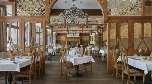 Elegancka restauracja w hotelu 5 gwiazdkowym, z drewnianymi zdobieniami i przytulnym kominkiem.