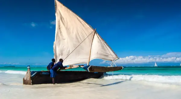 Dhow na plaży, gotowy do rejsu. Zastanawiasz się, ile się leci na Zanzibar? Ta łódź oferuje alternatywną, morską podróż.