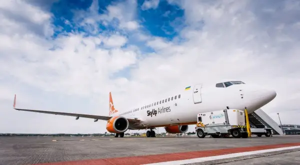Samolot SkyUp Airlines gotowy do startu. W tle błękitne niebo z chmurami.