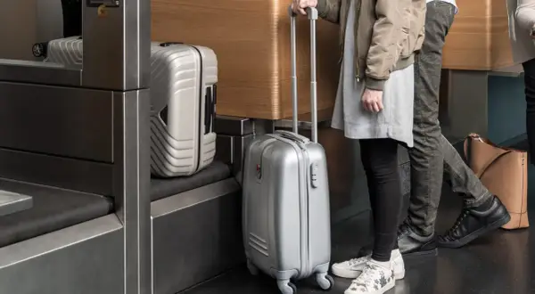 Osoby z bagażem podręcznym Austrian Airlines czekają w kolejce. Srebrne walizki gotowe do podróży.
