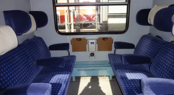 Wnętrze wagonu Intercity z niebieskimi siedzeniami. Czekam, aż zwolnią się miejsca dla niepełnosprawnych.