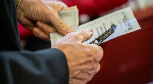 Dłonie trzymające bilety na pociąg, pokazujące, jak kupić bilet na pociąg w Norwegii.