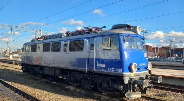 Niebiesko-szara lokomotywa PKP Intercity EP07-1001 na torach kolejowych.
