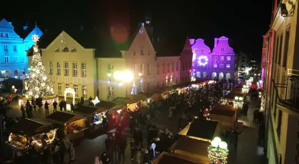 Tłoczny jarmark bożonarodzeniowy Olsztyn nocą. Rozświetlona choinka, stragany i kolorowe iluminacje budzą świąteczny nastrój.
