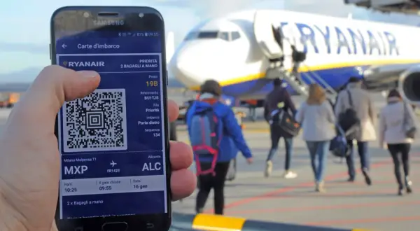 Karta pokładowa to bilet Wizzair na telefonie, z kodem QR, na tle samolotu Ryanair i pasażerów idących na pokład.