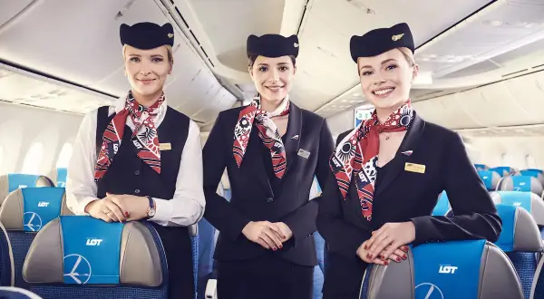 Trzy uśmiechnięte stewardessy LOT w eleganckich mundurkach. Zastanawiasz się, ile zarabia stewardessa LOT?