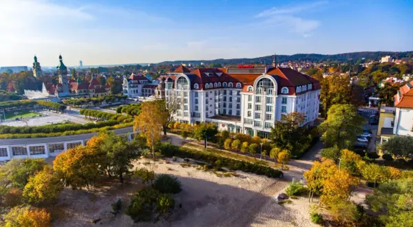 Hotel Sheraton Sopot z widokiem na plażę i jesienne drzewa.
