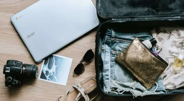 Przygotowania do podróży: swiss bagaż podręczny, laptop, aparat, okulary, sandały i kosmetyczka.