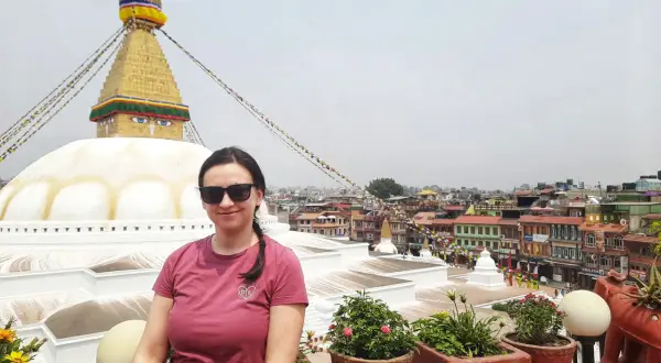 Kobieta w okularach przeciwsłonecznych pozuje na tle stupy Bodnath w Nepalu. Marzenie o lotach do Nepalu spełnione!