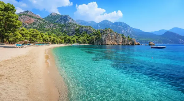 Piękna plaża z turkusową wodą i górami w tle. Idealne miejsce na wakacje, zastanawiasz się, ile się leci do Turcji?