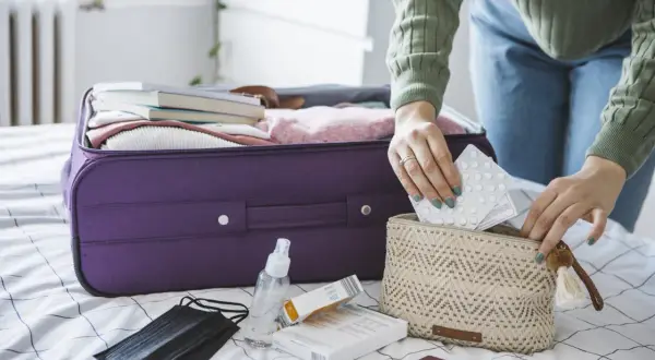 Pakowanie leków do bagażu podręcznego, by wiedzieć jak przewozić leki w samolocie Ryanair. W kosmetyczce tabletki, obok maseczka i płyn do dezynfekcji.