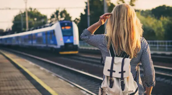 Dziewczyna z plecakiem czeka na pociąg, który zabierze ją do miast nad morzem.
