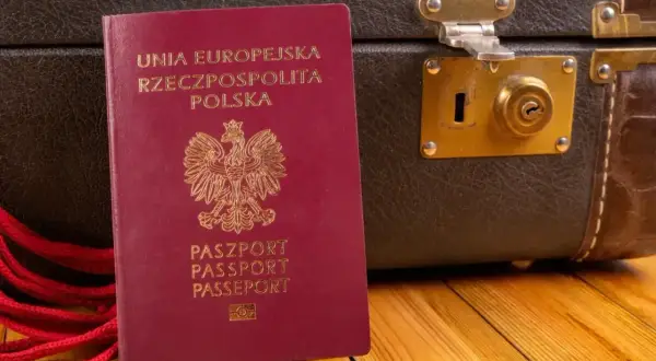 Czerwony paszport RP i stara walizka. Czy do Czarnogóry potrzebny jest paszport? Tak, ten dokument jest niezbędny do podróży.