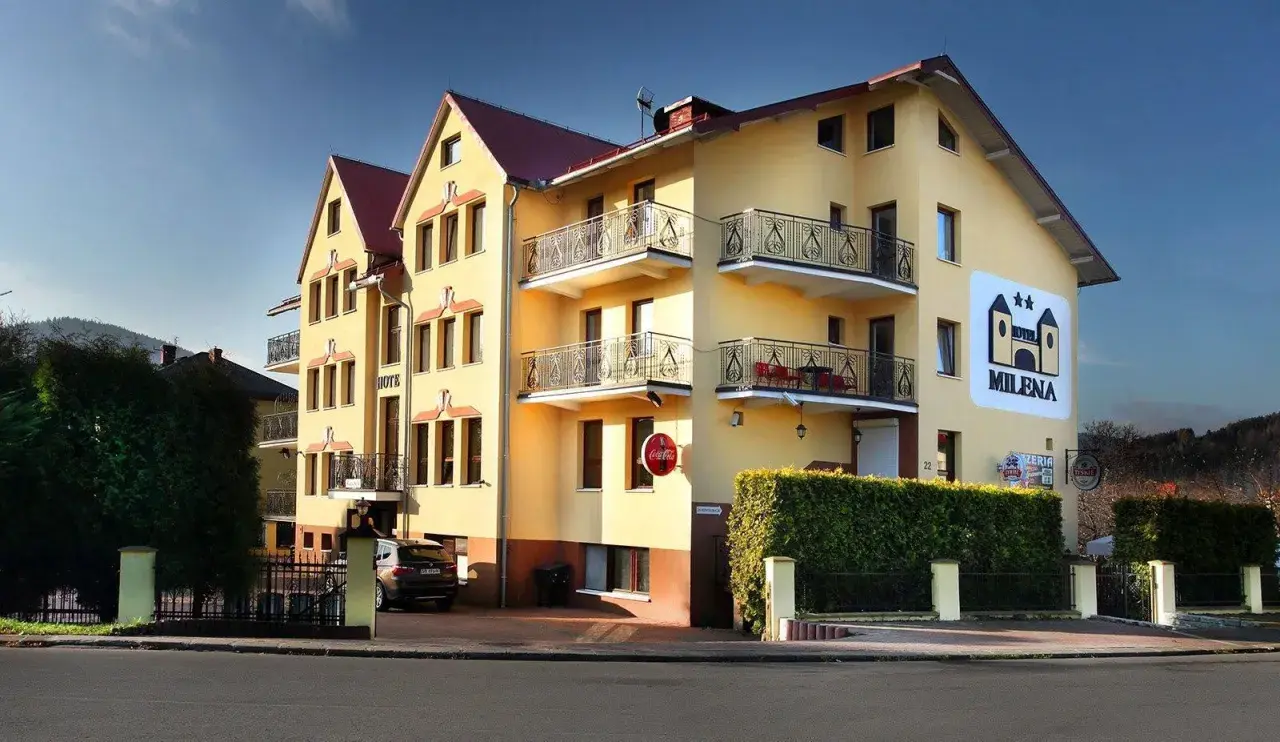 Żółty budynek hotelu Milena w Milówce z balkonami i logo hotelu.