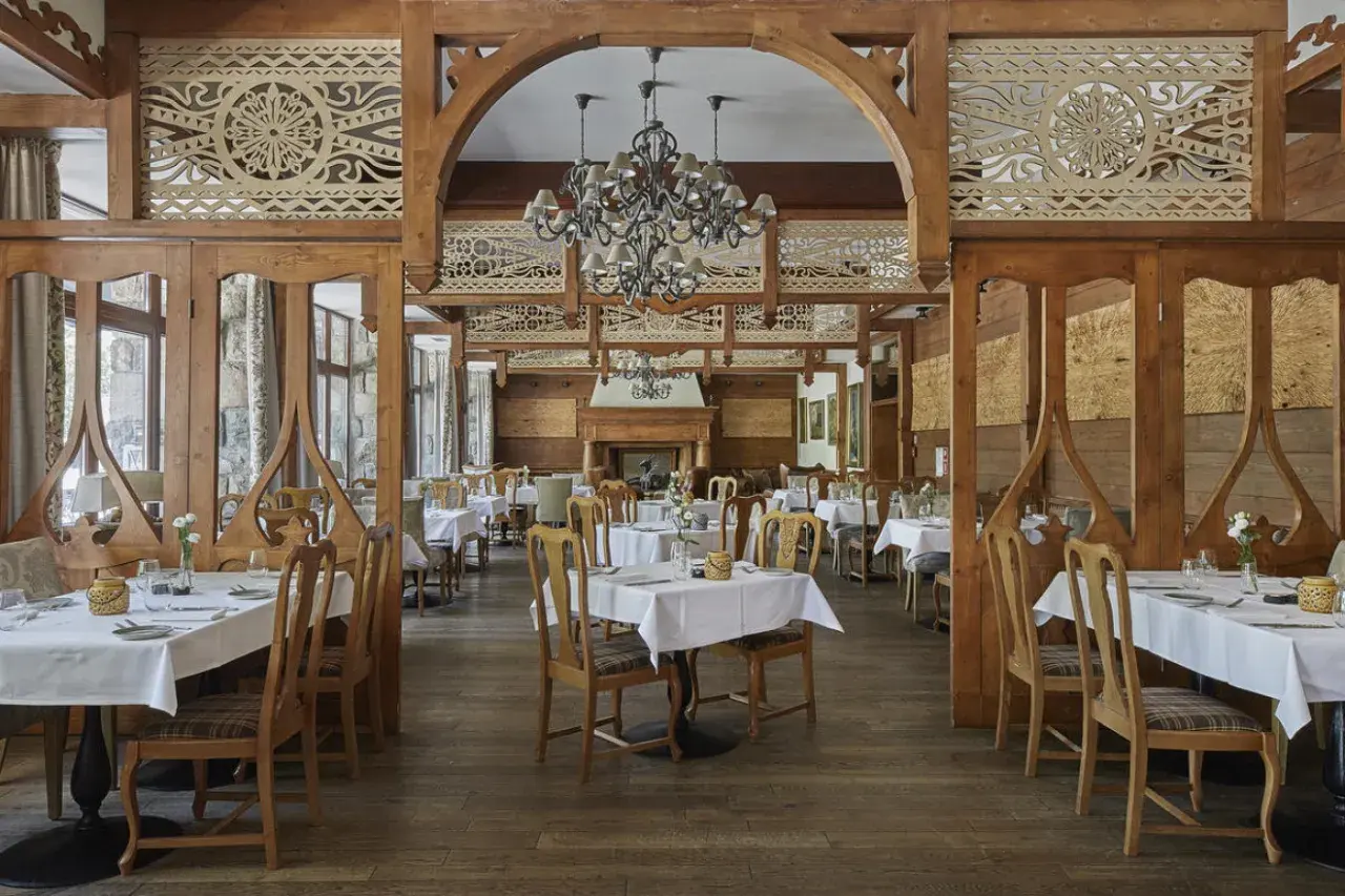 Elegancka restauracja w hotelu 5 gwiazdkowym, z drewnianymi zdobieniami i przytulnym kominkiem.