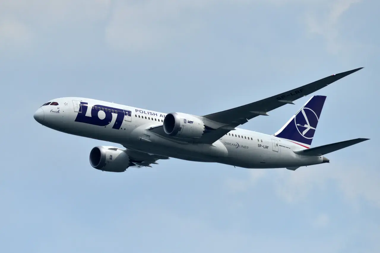 Samolot LOT Polish Airlines z numerem lotu SP-LRF wznosi się na błękitne niebo.