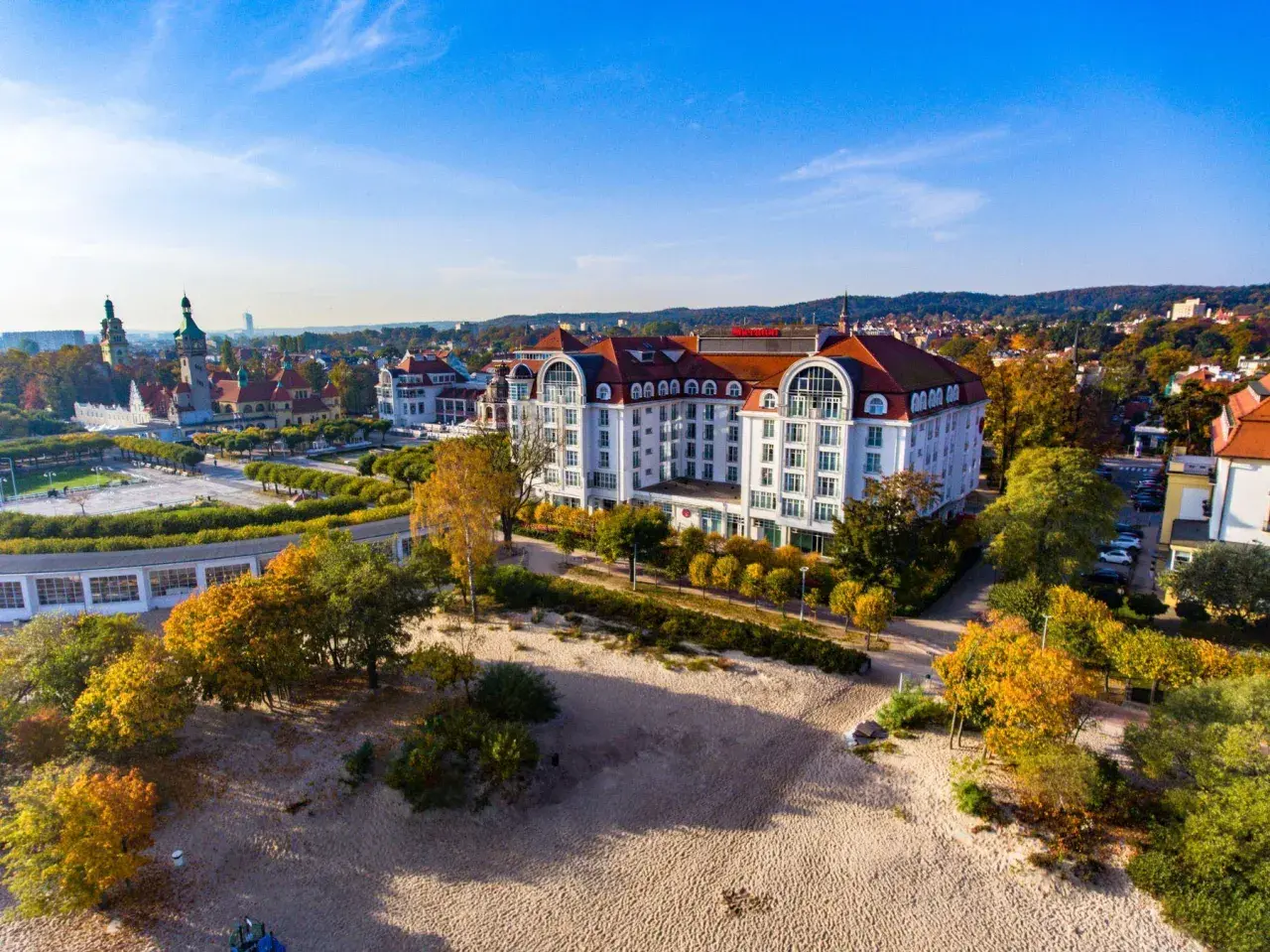 Hotel Sheraton Sopot z widokiem na plażę i jesienne drzewa.