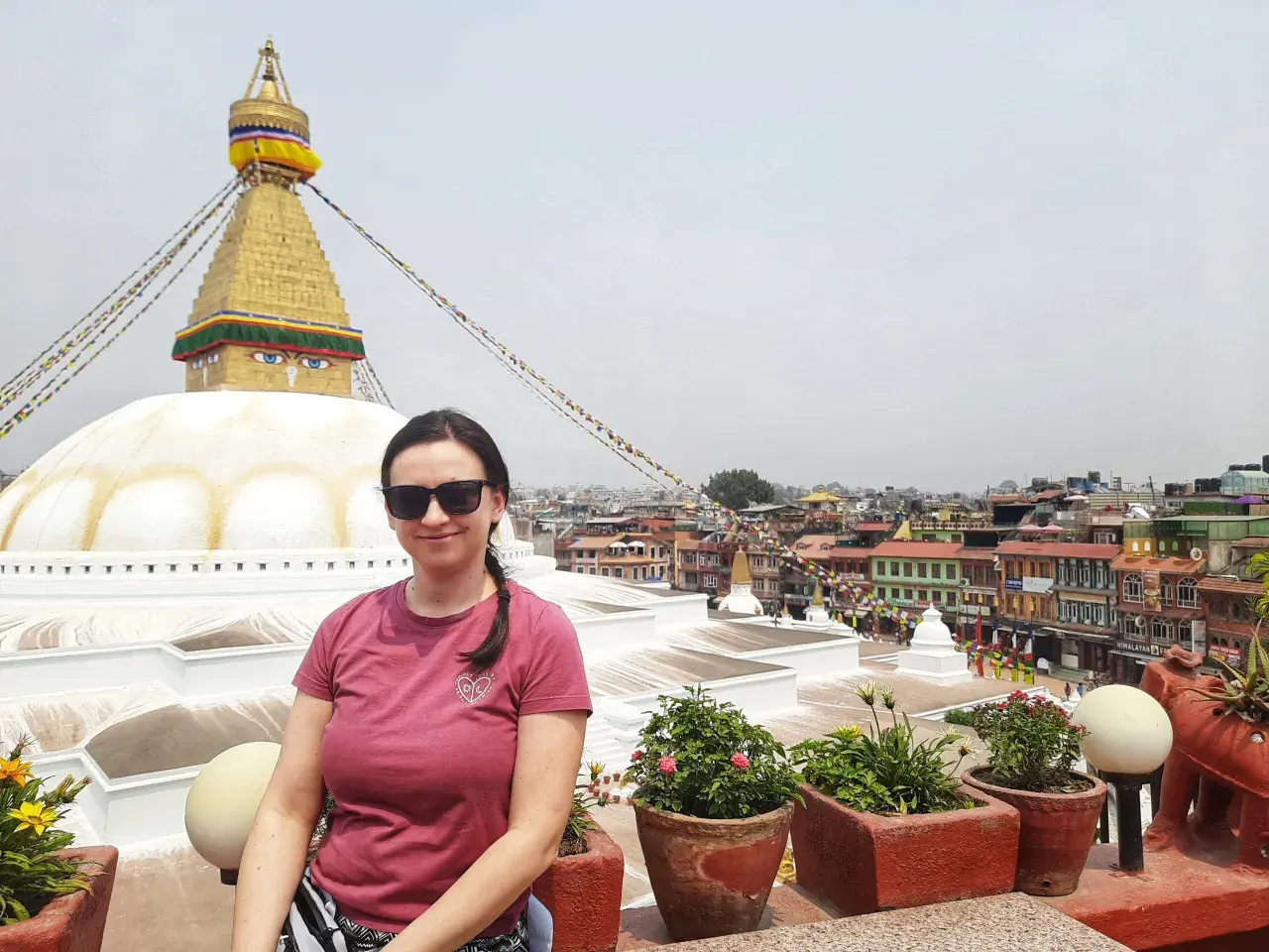 Kobieta w okularach przeciwsłonecznych pozuje na tle stupy Bodnath w Nepalu. Marzenie o lotach do Nepalu spełnione!
