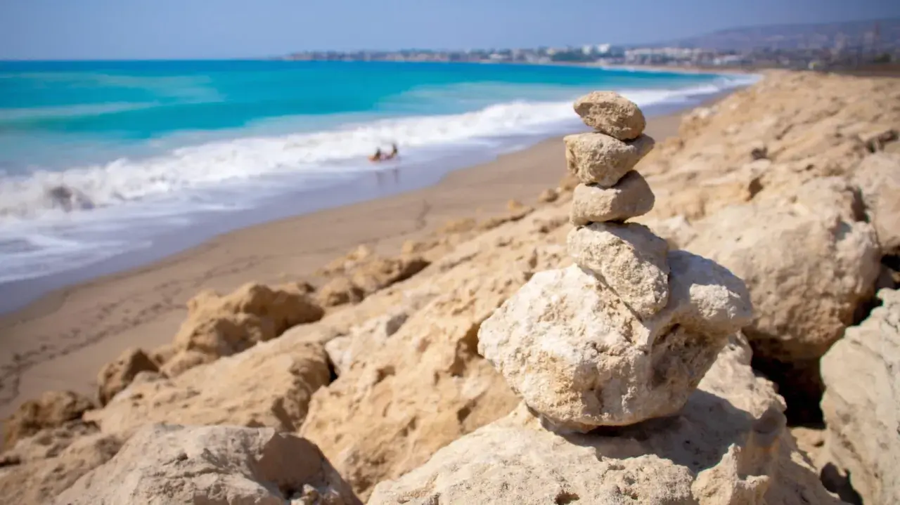Kamienna wieża na skalistym brzegu, w tle turkusowe morze i piaszczyste plaże Pafos.