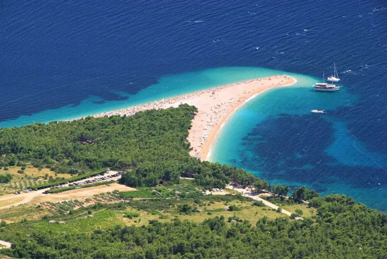 Zloty piasek i turkusowa woda na plaży w Chorwacji. Idealne miejsce na wakacje, pomyśl o bezpośrednie loty do chorwacji!