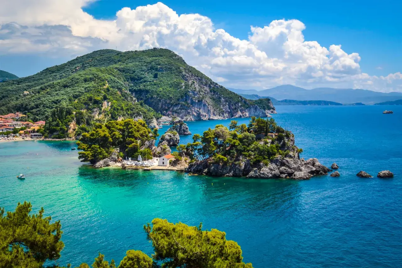 Malownicze **Lefkada loty z Polski** to marzenie o rajskich wakacjach. Widok na turkusowe morze, zielone wzgórza i urokliwą zatoczkę z białą kapliczką.