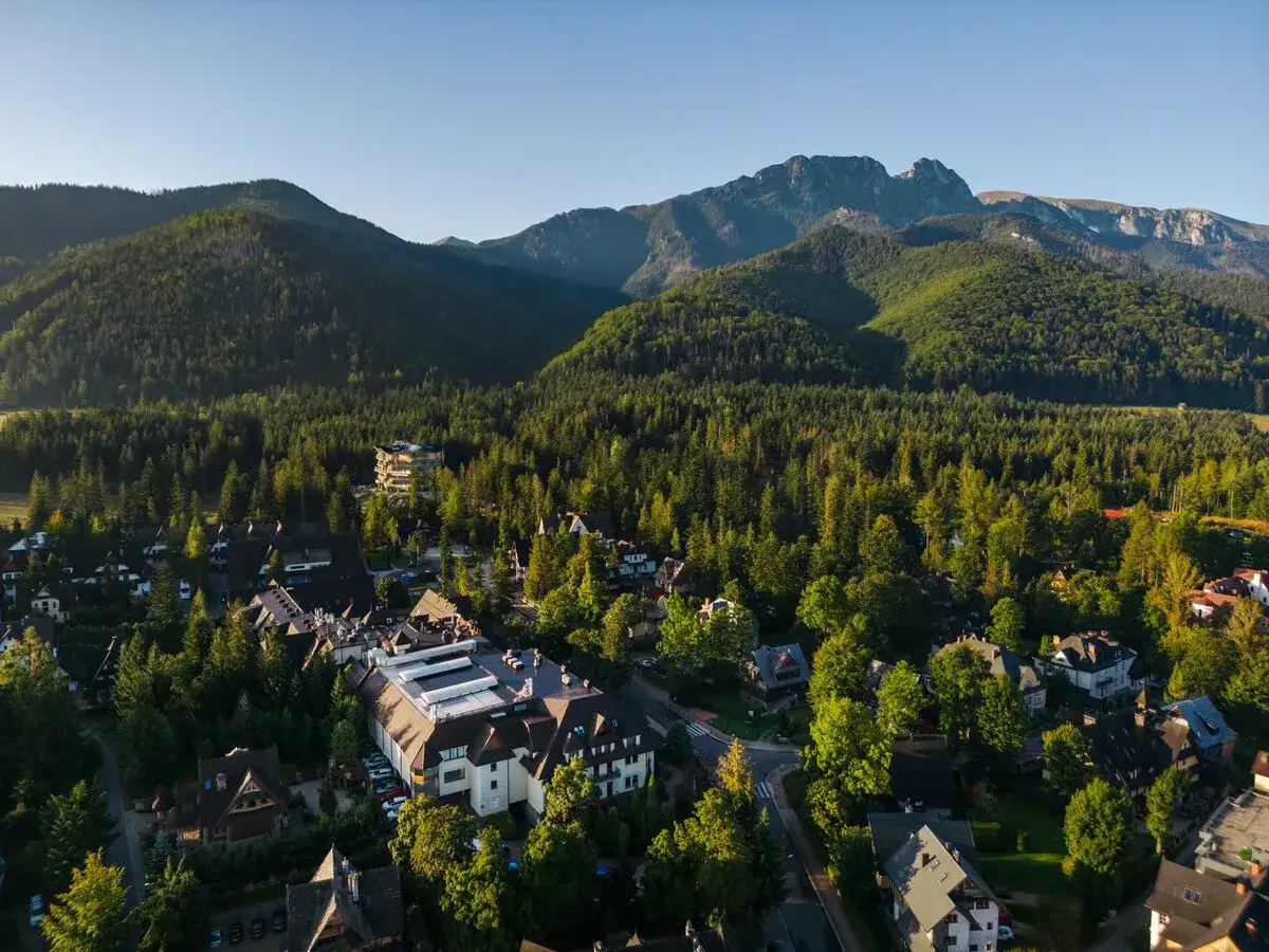 Widok z lotu ptaka na hotel Belvedere Resort & Spa otoczony lasem i górami.