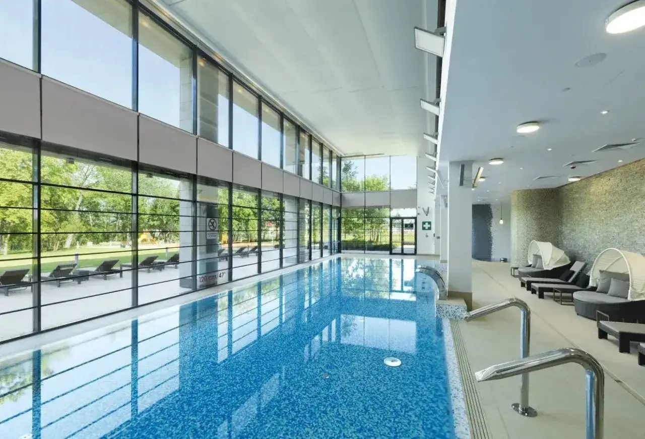 Basen hotelu Hilton Warszawa z widokiem na zieleń. Luksusowe leżaki i czysta woda zapraszają do relaksu.