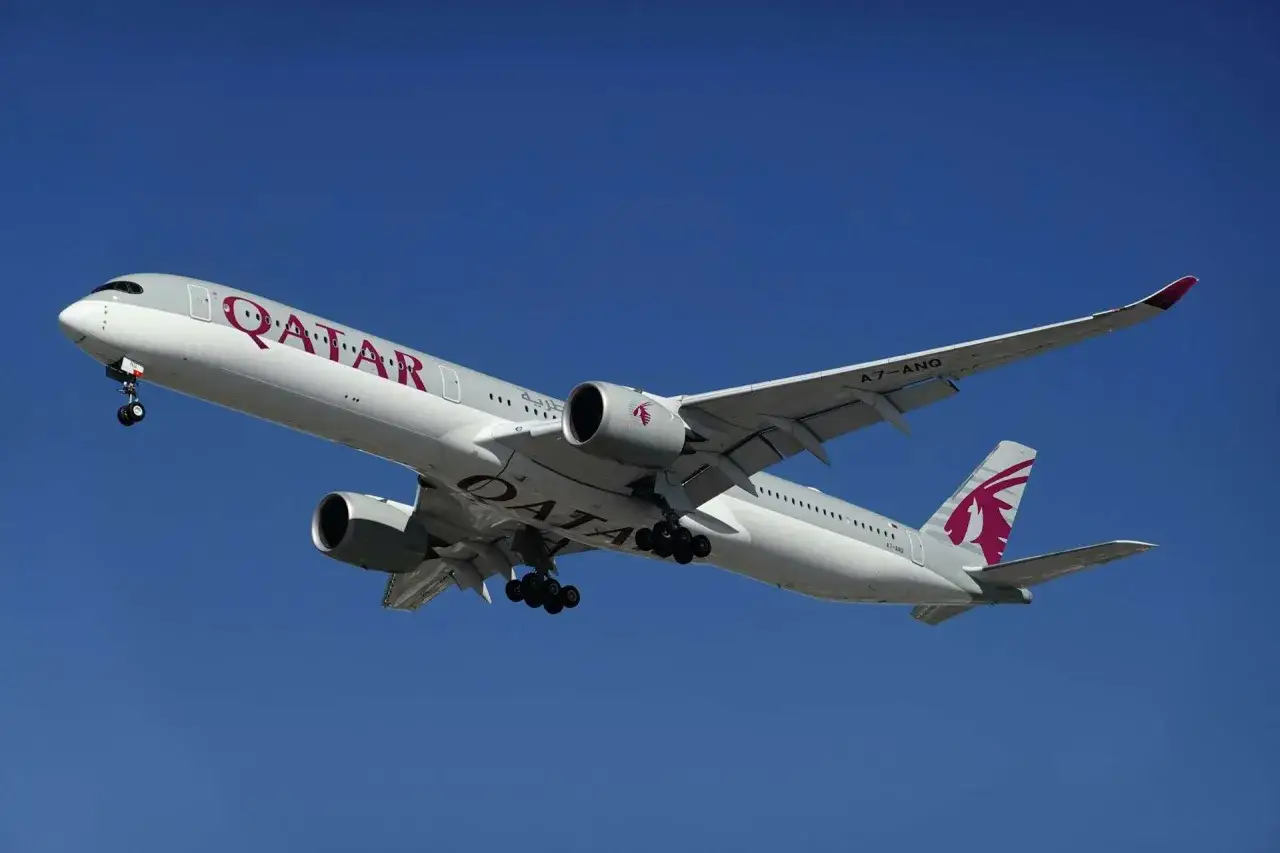 Samolot Qatar Airways z wysuniętym podwoziem, gotowy do lądowania. W bagażu podręcznym zmieści się wszystko, co potrzebne na podróż.