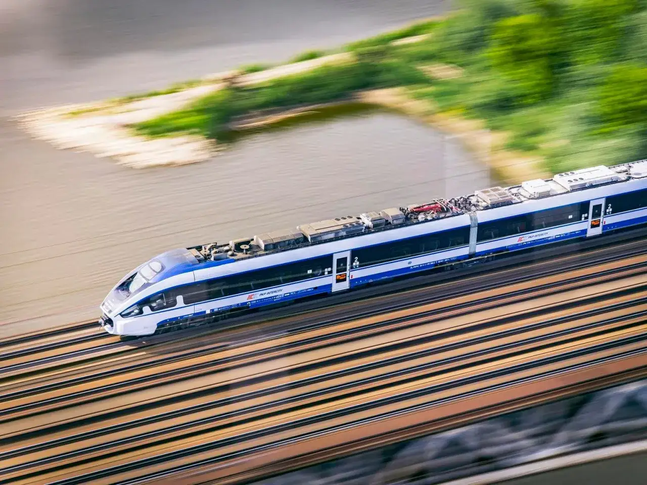 Szybki pociąg PKP Intercity mija rzekę. Zastanawiasz się, ile kosztuje bilet Intercity na podróż?